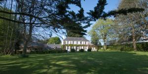 une grande maison avec une grande cour verdoyante plantée d'arbres dans l'établissement Manoir des Eperviers, à Quéven