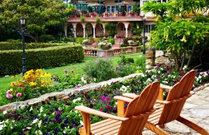 2 chaises en bois assises dans un jardin fleuri dans l'établissement La Playa Hotel, à Carmel