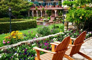 two wooden chairs sitting in a garden with flowers at La Playa Hotel in Carmel