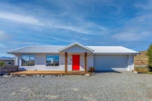 a small white house with a red door at Tekapo Blue in Lake Tekapo