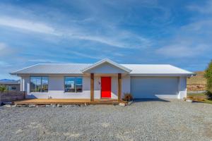 ein kleines weißes Haus mit einer roten Tür in der Unterkunft Tekapo Blue in Lake Tekapo