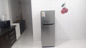 a stainless steel refrigerator in a kitchen with white tiles at Moderno Departamento Céntrico c/ Wifi Empresarial in Tarija