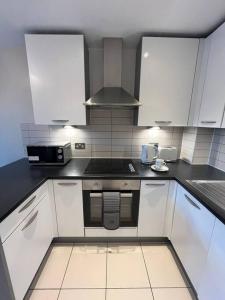 cocina con armarios blancos y fogones en Pettit Apartments - Central "Free Parking" en Liverpool