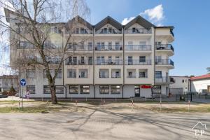 ein großes weißes Gebäude mit einem Baum davor in der Unterkunft Apartament KLIF&FALA Dziwnówek nad morzem EPapartamenty in Dziwnówek