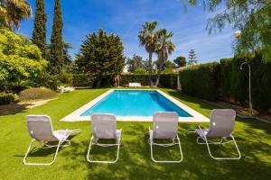 einen Garten mit Stühlen und einem Pool in der Unterkunft PIZARRA Planetcostadorada in Tarragona