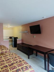 a hotel room with a desk and a flat screen tv at Residents Suites Liberty in Liberty