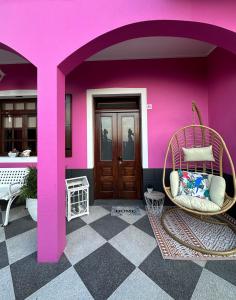 a room with a pink wall and a wicker chair at Residência Mendonça in Faial