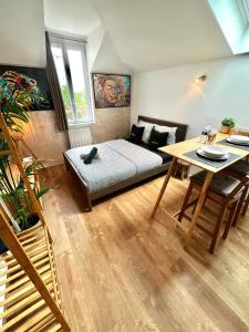 een woonkamer met een bed en een tafel bij Studio Douillet Hypercentre 12 min de Paris in Enghien-les-Bains