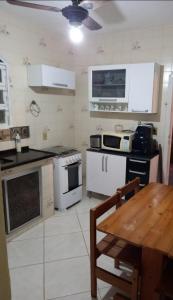 a kitchen with white appliances and a wooden table at CASA EM PRAIA SECA in Araruama