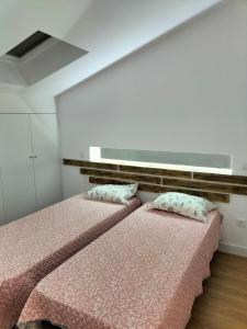 twee bedden in een kamer met roze lakens en kussens bij Casa do passadiço in Vieira do Minho