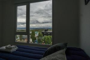 Habitación con ventana, cama azul y vistas. en Gente del Sur - Goleta en Ushuaia