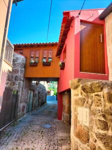 een steegje tussen twee gebouwen met een rood gebouw bij Casa do passadiço in Vieira do Minho