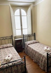 a bedroom with two beds and a window at Serena Apartment in Lucca