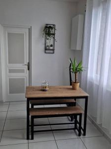 una mesa y un banco en una habitación con una planta en Appart 10 minutes de rouen, en Oissel