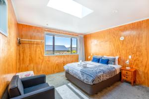 a bedroom with a bed and a chair and a window at Tekapo Blue Cottage in Lake Tekapo