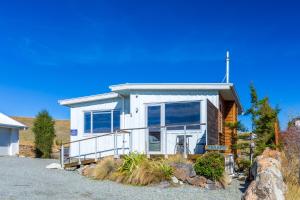 a white house with large windows on a street at Tekapo Blue Cottage in Lake Tekapo