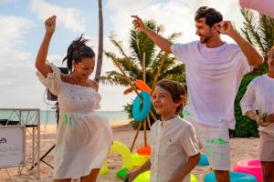 Paradisus Playa del Carmen - Riviera Maya - All Inclusive في بلايا ديل كارمن: رجل وامرأه واطفال يلعبون على الشاطئ