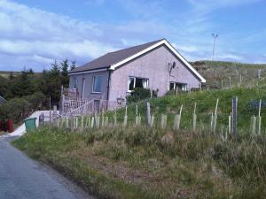 een huis aan de zijkant van een heuvel met een hek bij Tigh na Fraoch in Flashader