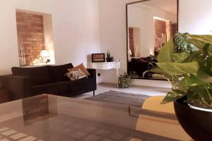 sala de estar con sofá negro y espejo en L'Archetto Apartment, en Civitavecchia