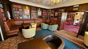 uma biblioteca com um sofá, cadeiras e livros em NELSON Hotel em Great Yarmouth