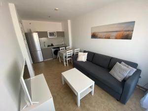 sala de estar con sofá azul y cocina en Punta Umbria ideal apartamento Enebrales, en Punta Umbría