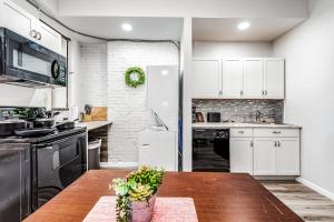 a kitchen with white cabinets and a wooden table at Park Ave Townhome w parking by CozySuites in Saint Louis