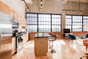 a large kitchen with a counter and some chairs at CozySuites Gorgeous 2BR penthouse w Skyline view in Saint Louis