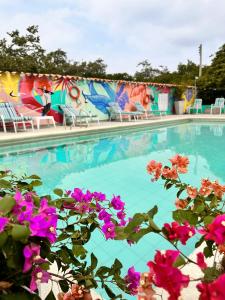 a swimming pool with blue water and pink flowers at Hotel Los Veleros Santa Marta in Santa Marta