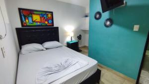 1 dormitorio con 1 cama blanca y una pintura en la pared en Hotel Aqua lux, en Medellín
