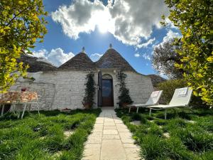 uma casa com telhado de palha e duas cadeiras de jardim em Trulli Barsento em Alberobello