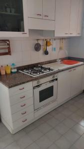 una cucina con piano cottura e armadietti bianchi di La casa di Alba ad Alba Adriatica