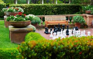 a chess game in a garden with a bench and flowers at La Playa Hotel in Carmel