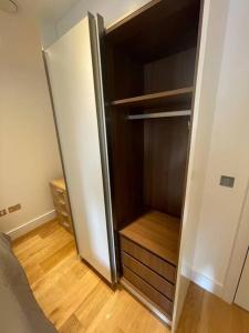 een lege kast met een koelkast in een kamer bij Vibrant flat in the city centre in Slough
