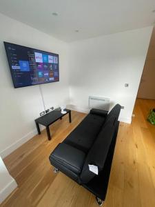 a living room with a black couch and a tv at Vibrant flat in the city centre in Slough