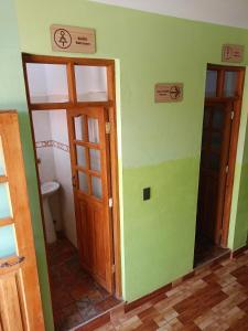 a bathroom with two doors and a toilet at Hostal Torotoro in Torotoro