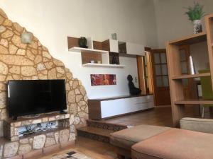 a living room with a tv and a stone wall at Mirariu in Els Muntells