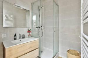 a bathroom with a glass shower and a sink at le karibu appartement confort tout équipé in Lagnieu