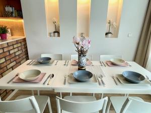 バラトンフレドにあるBonita Apartman & Garageの白いテーブル(椅子、皿、花瓶付)