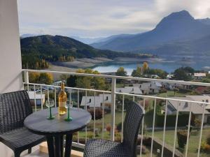 einen Tisch mit zwei Gläsern Wein auf dem Balkon in der Unterkunft Superbe appartement avec vue sur lac et montagnes - Station de ski 10 min in Chorges