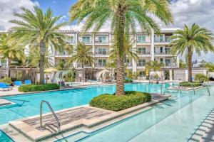 Una piscina con palmeras frente a un edificio. en Cabanas and Sunsets, en Inlet Beach