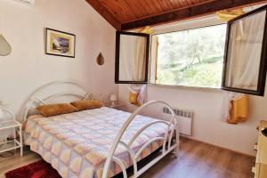 sypialnia z białym łóżkiem i oknem w obiekcie Appartement du Parc w mieście Patrimonio