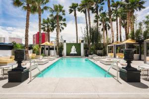 a swimming pool with palm trees and a fountain at The Lexi Las Vegas in Las Vegas