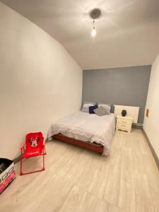 um quarto com uma cama e uma cadeira vermelha em Appartement de 100 mc avec vue panoramique à 50 mn de Strasbourg. em Senones