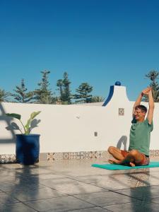 una mujer sentada en una alfombra haciendo yoga en El MOJA SURFHOUSE, en Sidi Ifni