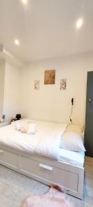 um quarto com uma cama grande e lençóis brancos em Le petit havre de paix, Proche Paris-Disney-Asterix-Aéroport CDG em Pavillons-sous-Bois