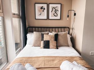 um quarto com uma cama com almofadas e uma janela em The Aspect, by Solace Stays em Cardiff