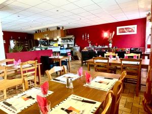 a restaurant with wooden tables and a red wall at Auberge Le Beaulieu -Cantal in Beaulieu