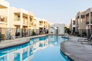 a pool at a hotel with tables and chairs at Red Desert Loft Resort 37 Pickleball Courts, Foosball, Resort Pool with Waterslide & Jacuzzi! in St. George