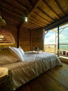 Cama grande en habitación con ventana grande en HakunaMatata glamping Pumba, en Salento