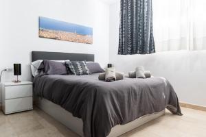 una camera da letto con un letto con un piumone grigio di Apartament Granollers Up Live I a Granollers